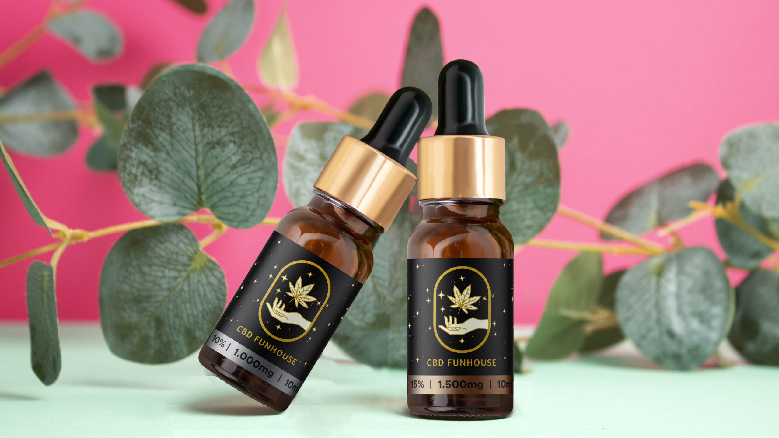 Amber glass dropper bottles different sizes with eucalyptus branch on pink background. Cosmetic container mock-up. Background for branding and packaging presentation. Natural skincare beauty product concept
